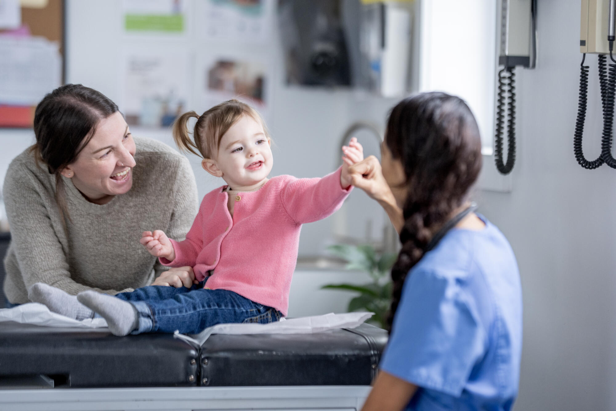 Caring Pediatric Visit With Mother, Daughter, And Nurse In A Clinic Setting